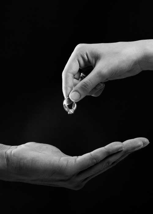 black and white close up image of woman handing man her wedding ring
