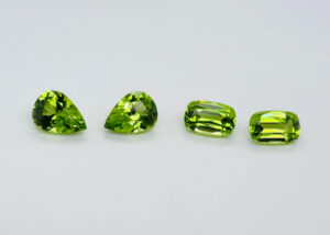 Four vibrant light green gemstones on grey background