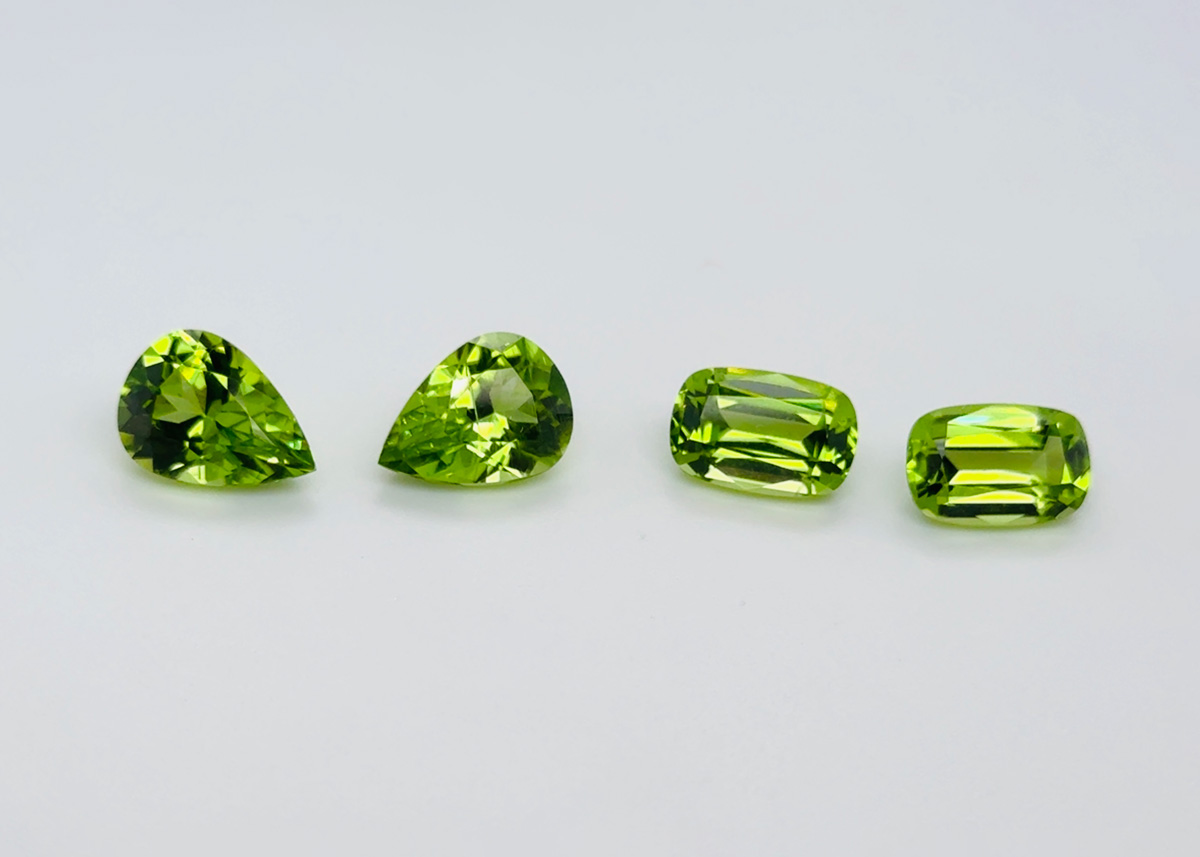 Four vibrant light green gemstones on grey background